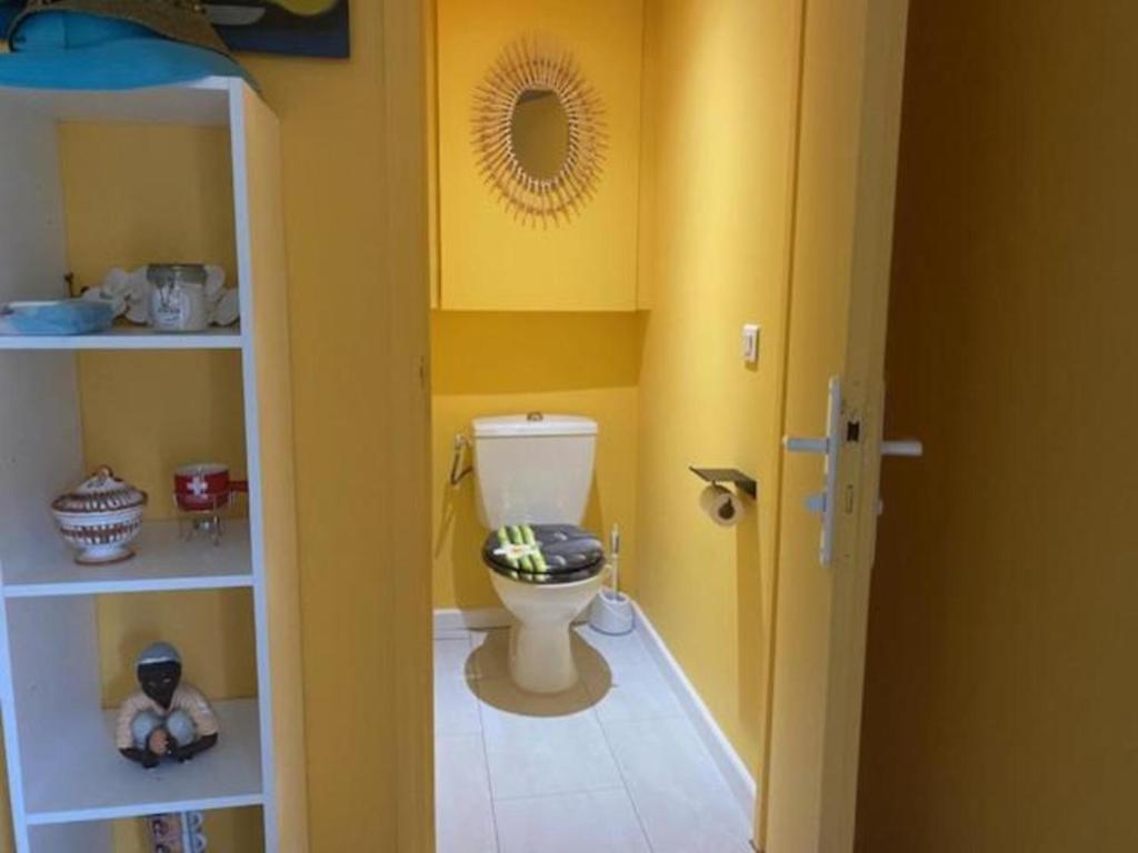 a bathroom with a toilet in a room with yellow walls at Sun Caraibes in Orient Bay