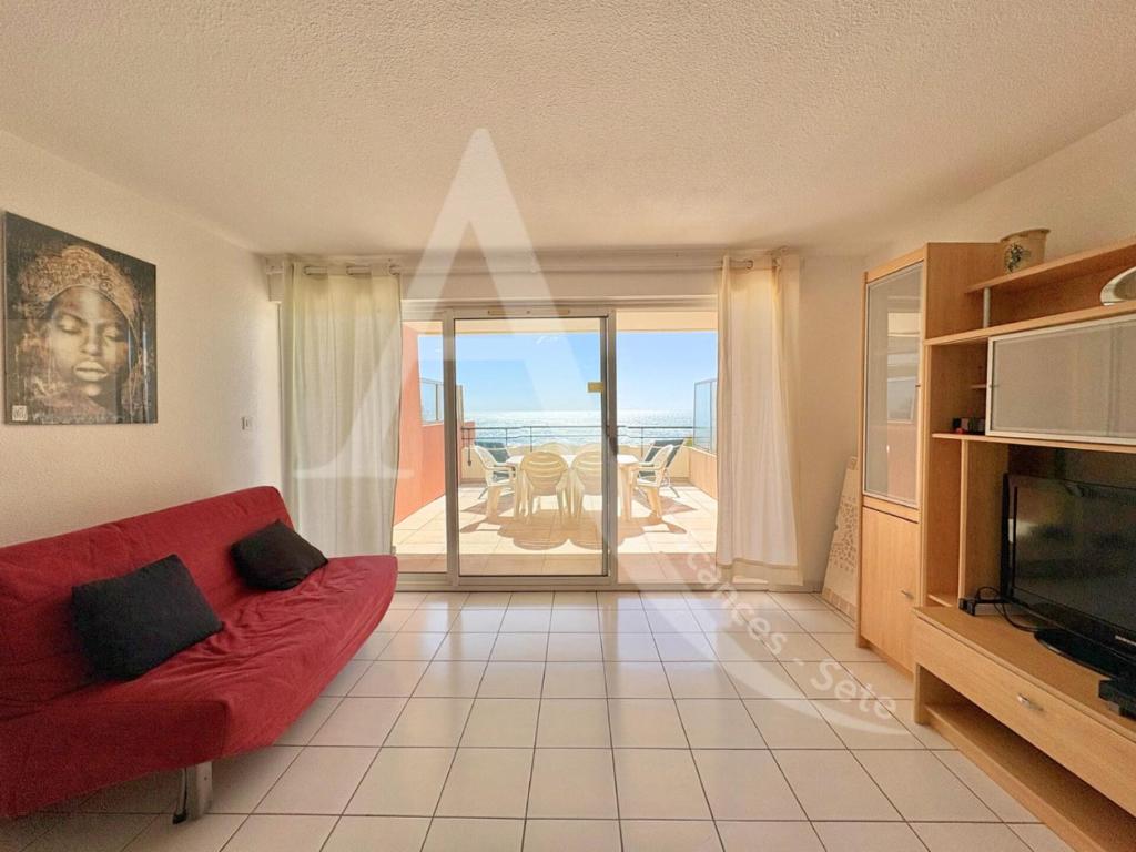 un salon avec un canapé rouge et une télévision dans l'établissement 2 CHAMBRES, LARGE TERRASSE 1ERE LIGNE MER, PISCINE, à Sète