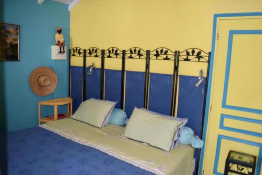 a bedroom with a bed with a blue wall at Sun Caraibes in Orient Bay