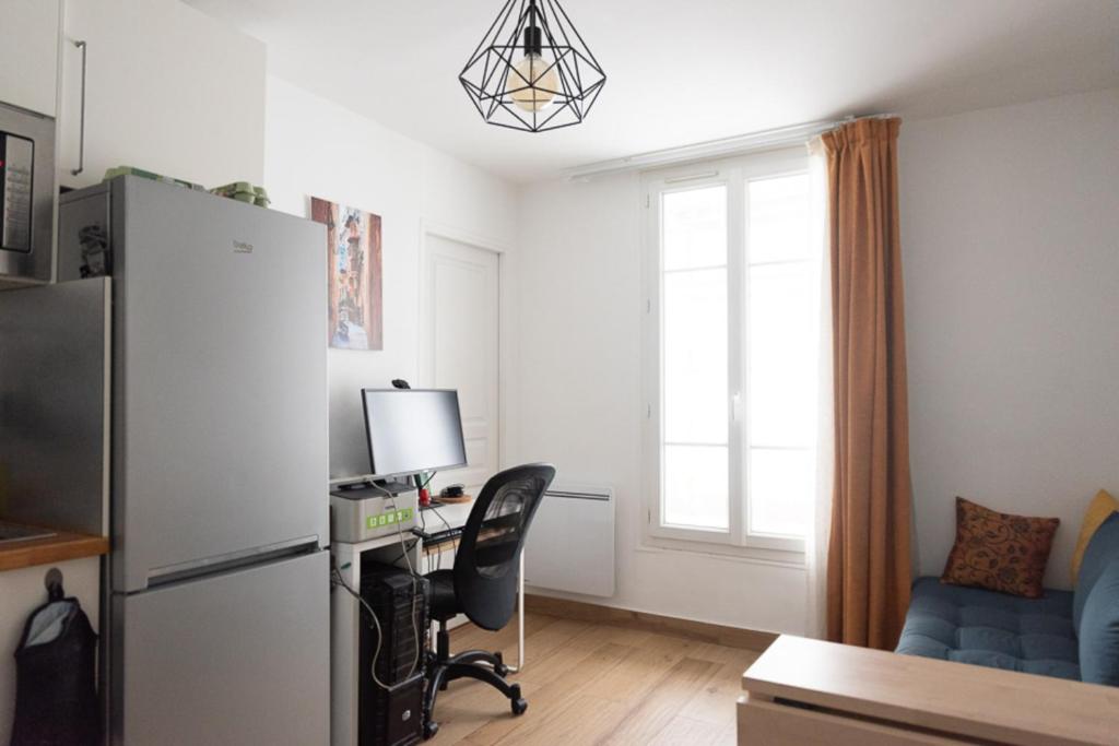 un salon avec un réfrigérateur et un bureau avec un ordinateur dans l'établissement Apartment of 26 m2 near the park of Belleville, à Paris