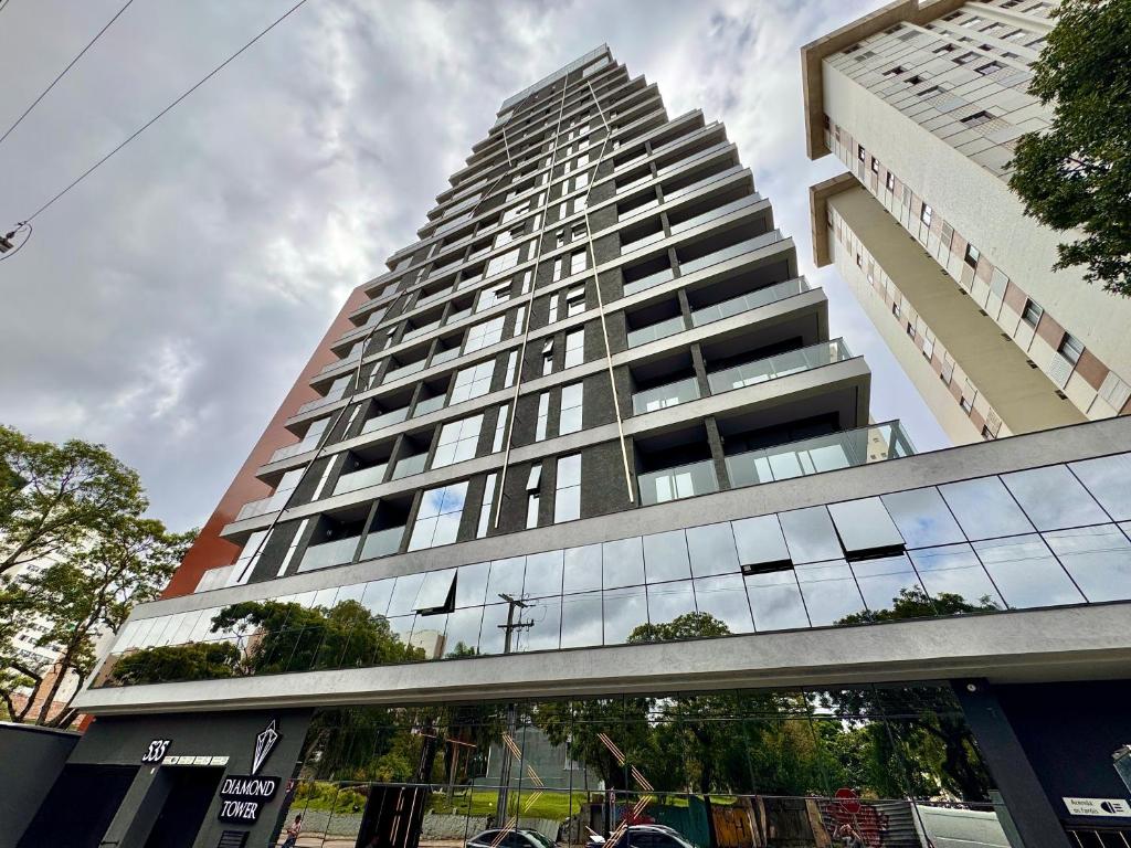 a tall building with a reflection of a building at Diamond Batel - Apartamentos by UROOMS in Curitiba