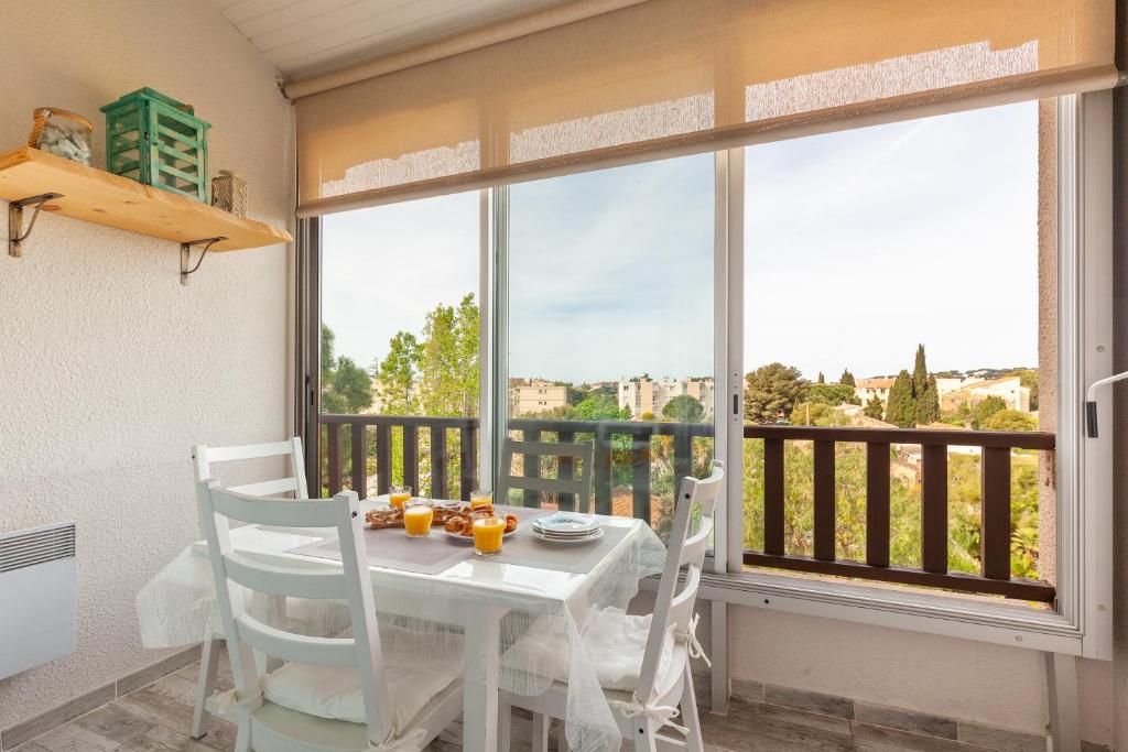 une salle à manger avec une table et des chaises et une grande fenêtre dans l'établissement Sanary Sur Mer,Soleil Et Douceur Il, à Sanary-sur-Mer