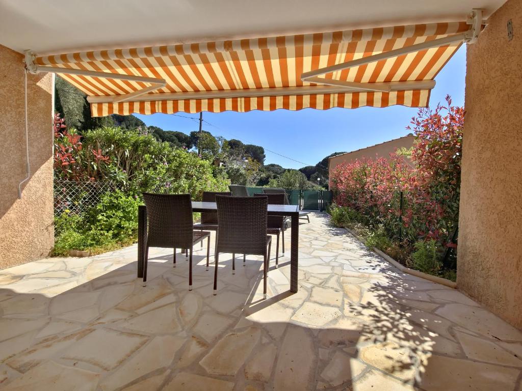 un patio avec une table et des chaises sous une pergola dans l'établissement Les Terrasses de Cavald'Or - T2 with pool, au Lavandou