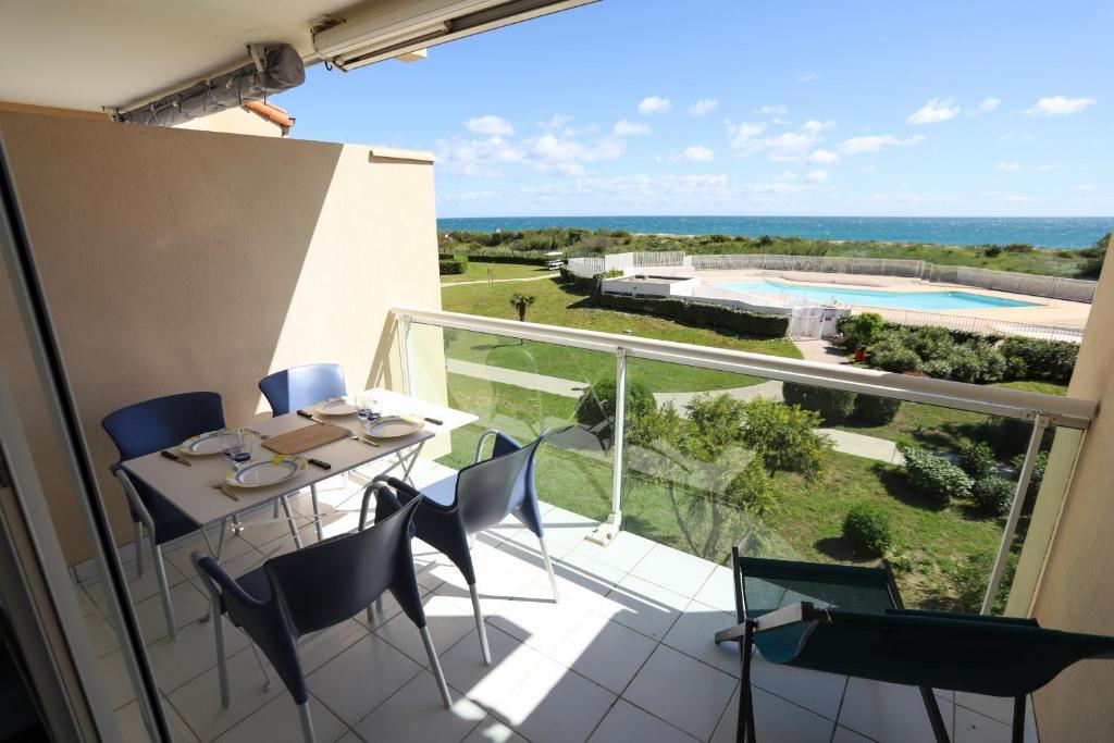 d'un balcon avec une table et des chaises et une vue sur la piscine. dans l'établissement St cyprien appart vue mer 2 a 4 personnes avec piscine, à Saint-Cyprien