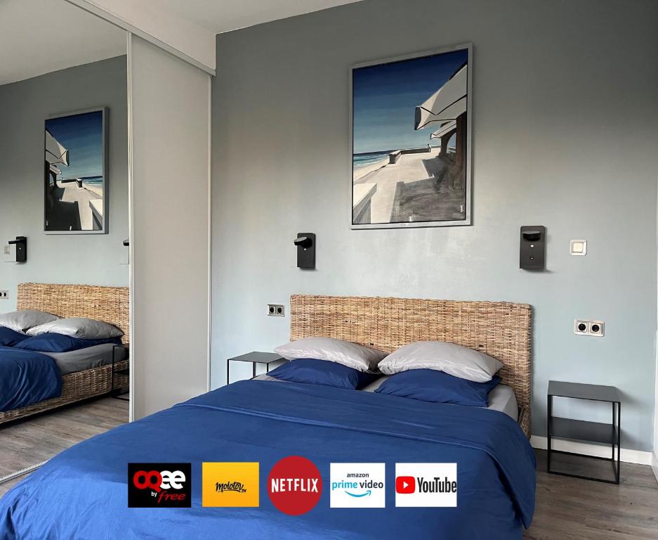 a bedroom with a bed with a blue comforter at Studio Luxe + jardin et terrasse in Pontoise