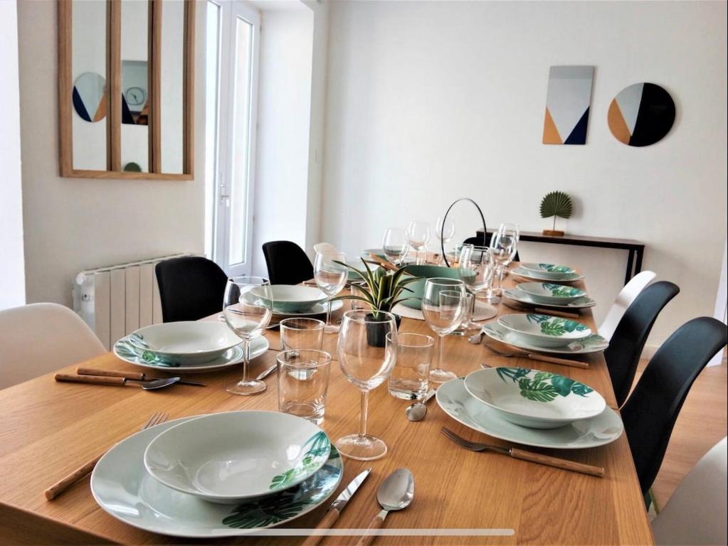 une table en bois avec des assiettes et des verres à vin dessus dans l'établissement La maison Haute, à Guer