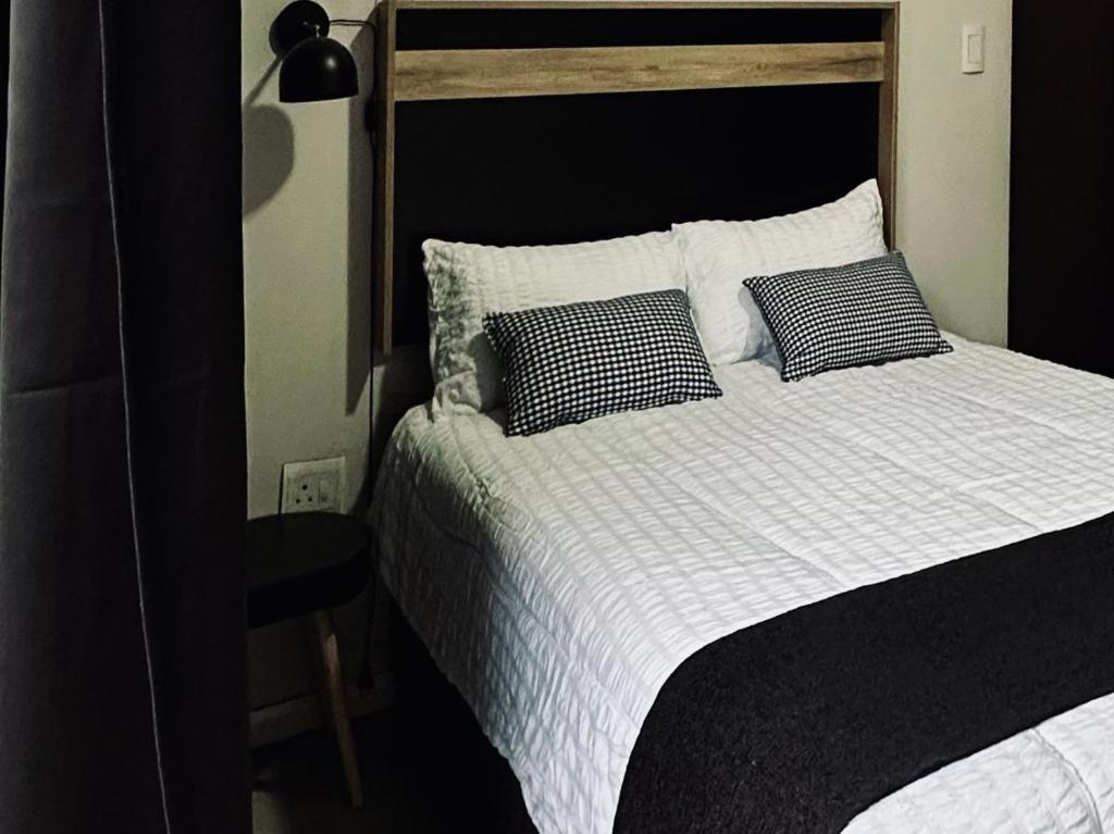 a bed with black and white sheets and pillows at Cosy Urban Apartment in Durban