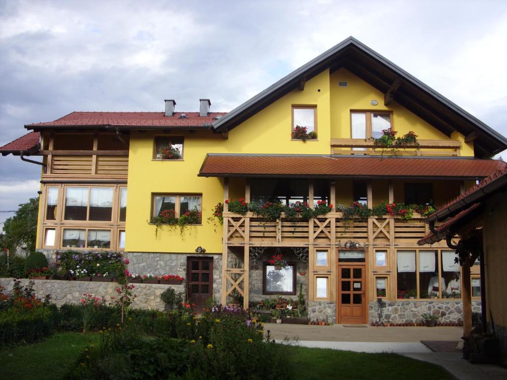 una casa amarilla con flores en el balcón en Tourist Farm Ob izviru Krupe en Semič