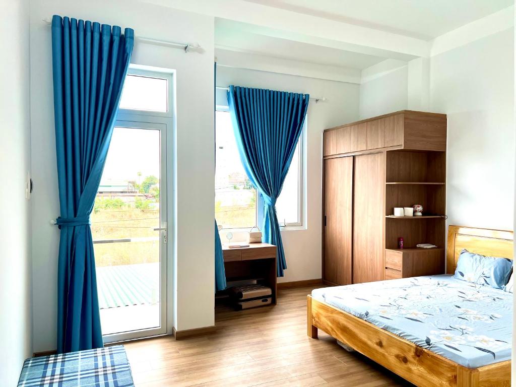 a bedroom with blue curtains and a bed and a window at Villa 1985 in Buon Ma Thuot