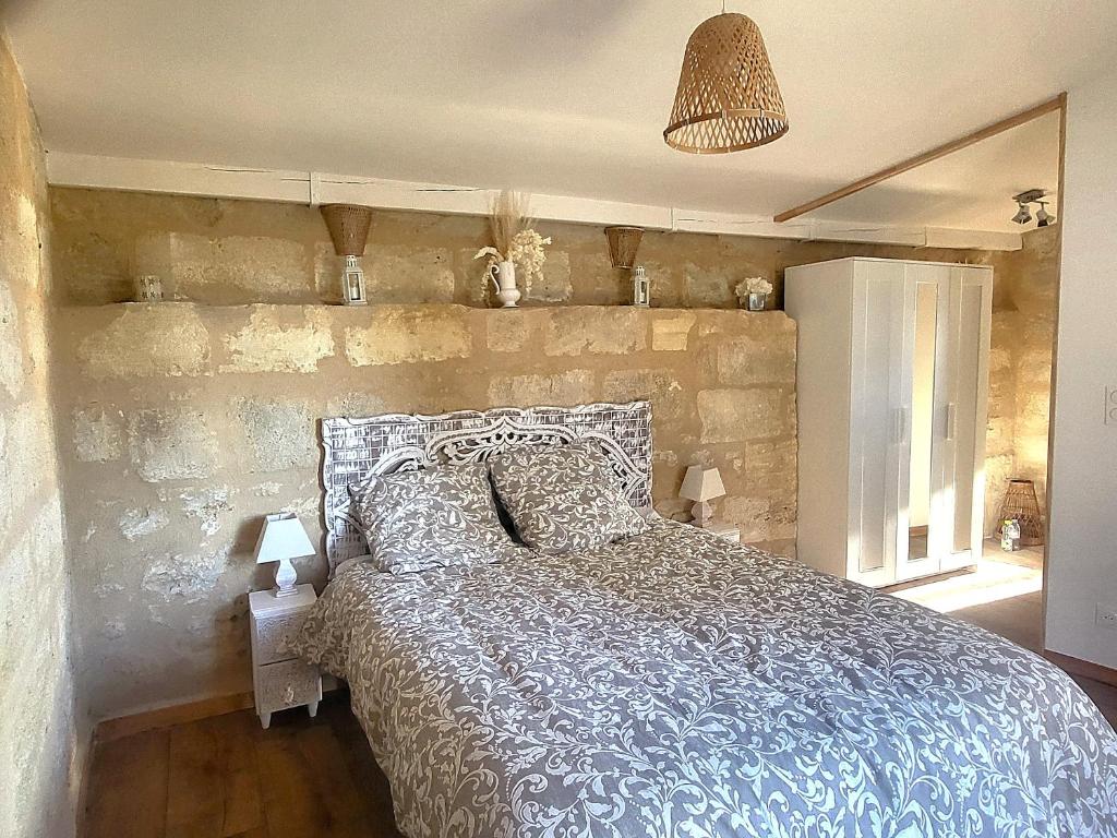 une chambre avec un lit avec un mur en pierre dans l'établissement La suite du Grand Cèdre, à Lussac