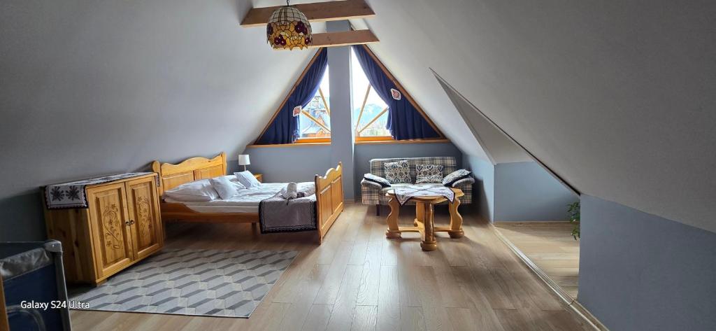 Cette chambre mansardée comprend un lit et une fenêtre. dans l'établissement Domek za Strugiem - pokoje i apartamenty, à Zakopane