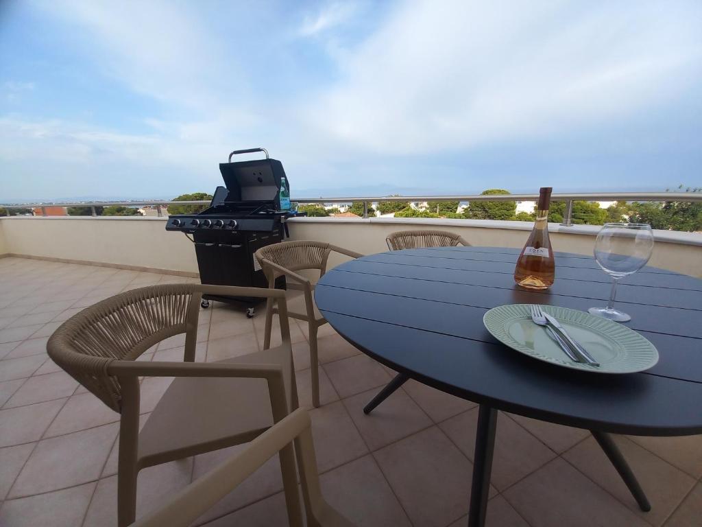 a blue table and chairs on a balcony with a grill and wine glass at Salty Sea Breeze in Artemida