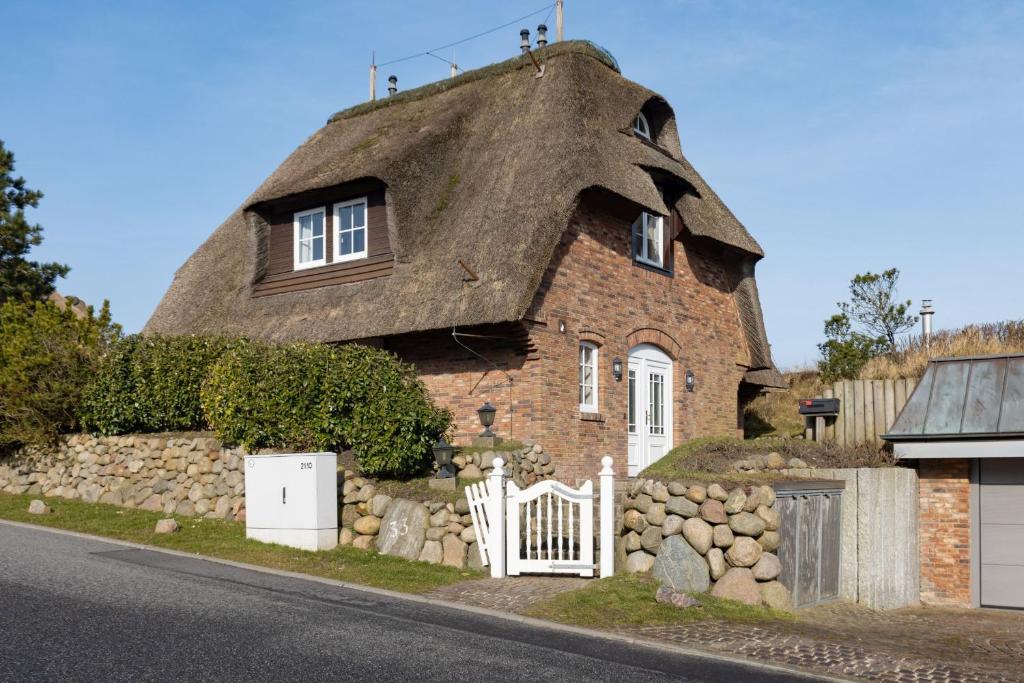 une vieille maison en briques avec un toit de chaume dans l'établissement Senenskiin, à List auf Sylt