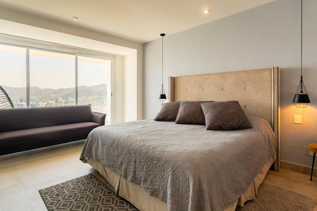 a bedroom with a bed and a couch and a window at Departamento en Brisas Diamante in Acapulco