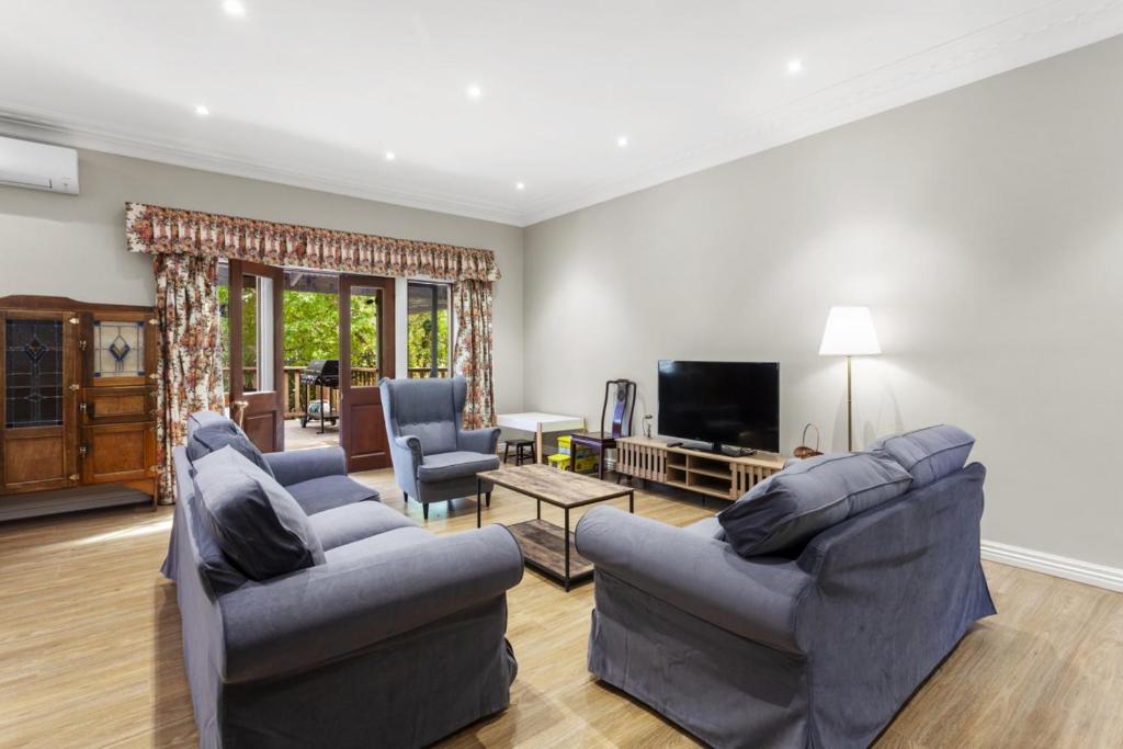 Una sala de estar con dos sofás y un televisor. en Birdstow Spacious peaceful Stay Sleeps Ten, en Wentworth Falls