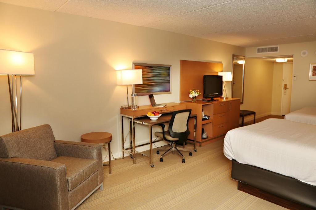 Una habitación de hotel con cama, escritorio y cama y una habitación con en enVision Hotel & Conference Center Mansfield-Foxboro, en Mansfield