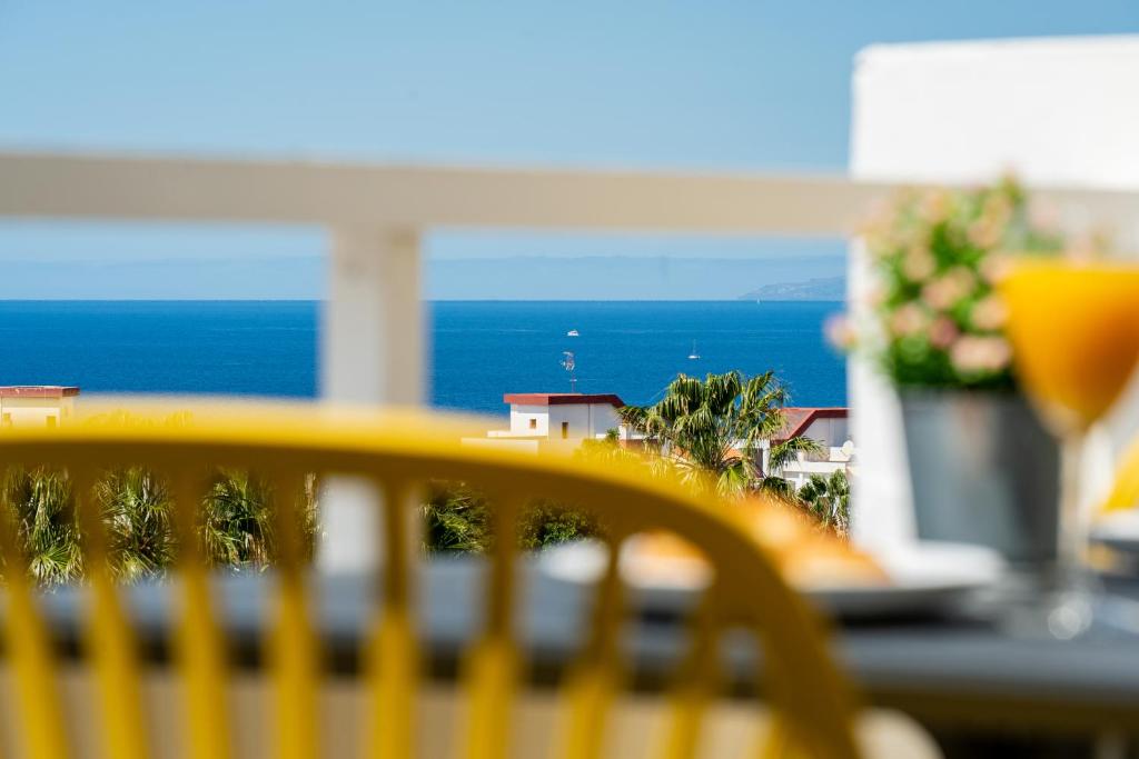 ein gelber Stuhl vor einem Tisch mit Blick auf das Meer in der Unterkunft Modern studio with ocean views and heated pool in Malibu Park in Adeje