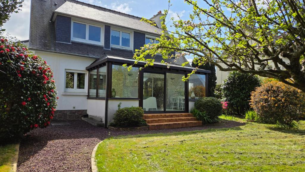 une maison avec une véranda et des portes en verre dans l'établissement Villa Roz Granit Perros-Guirec, à Saint-Quay-Perros