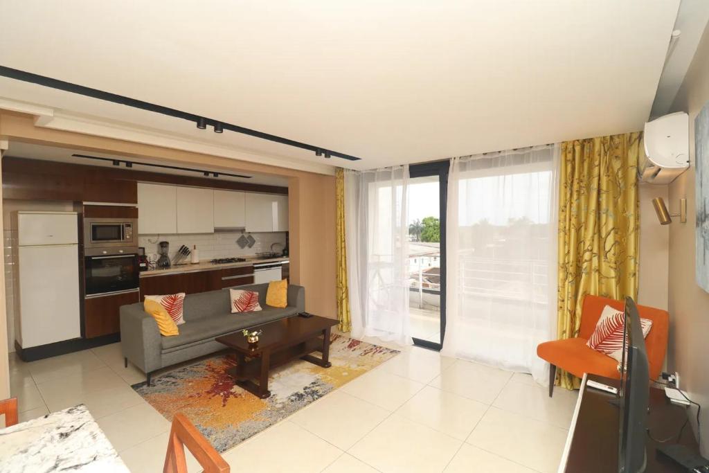 a living room with a couch and a kitchen at HE Appart 402 situé à Bonapriso hôtel de l'air avec salle de Gym in Douala