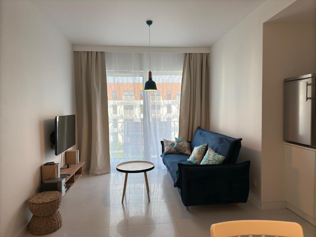 un salon avec un canapé bleu et une table dans l'établissement Baltic SEA apartament z dostępem do basenu,sauny ,jacuzzi i hali sportowej, à Gąski