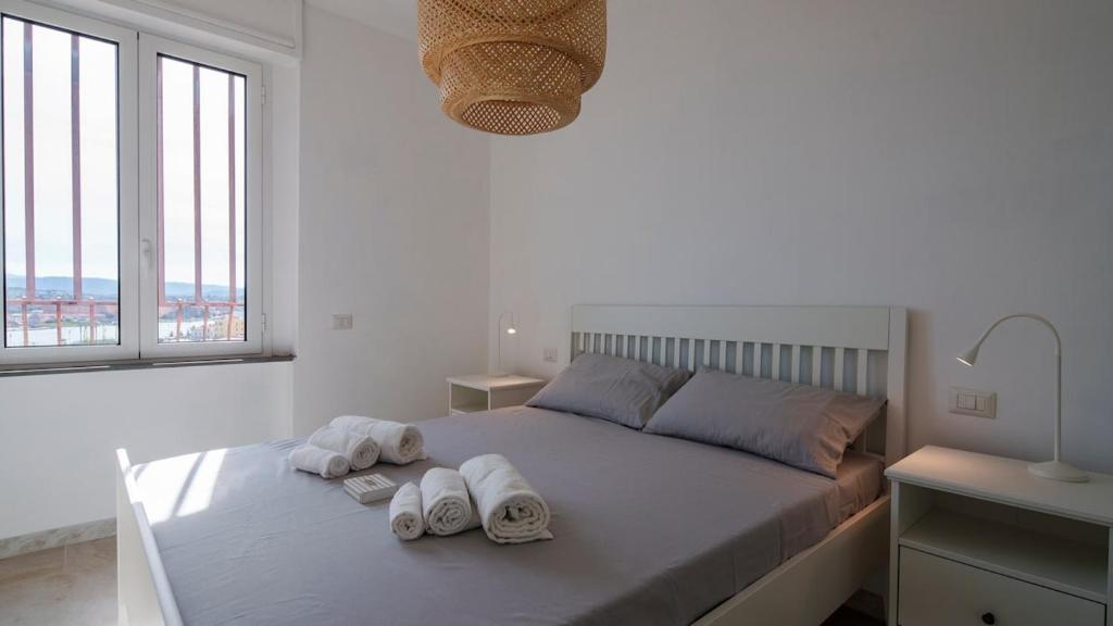 a white bedroom with a bed with towels on it at Panoramic Seaview in Olbia