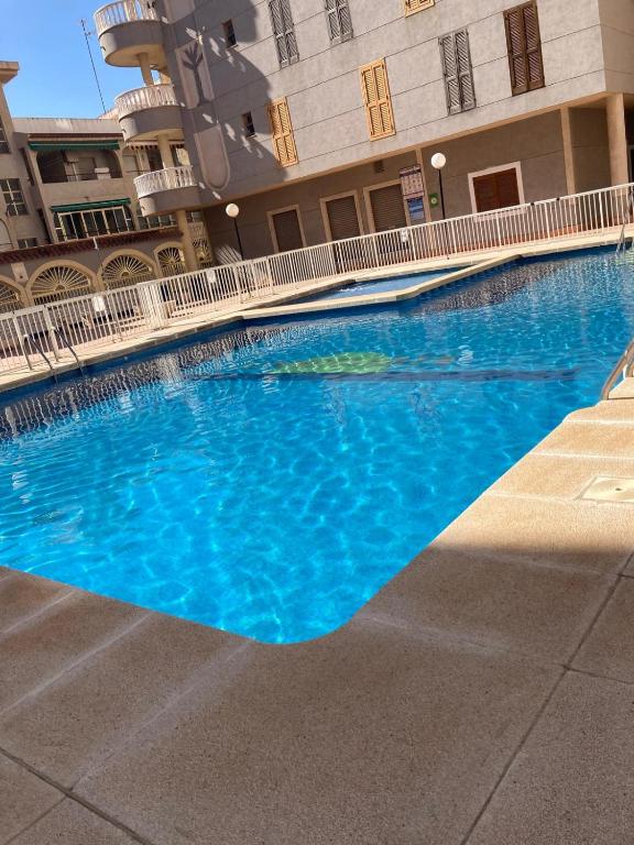una gran piscina azul frente a un edificio en Dos Playas Bonito Apartment, en Torrevieja