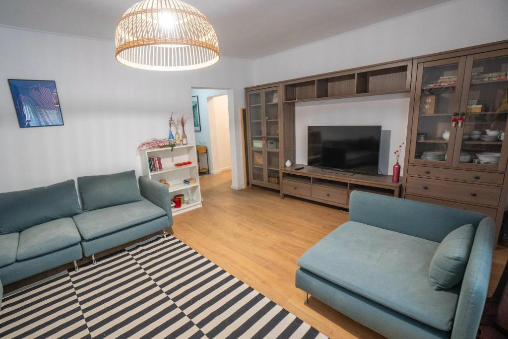 ein Wohnzimmer mit zwei blauen Sofas und einem Fernseher in der Unterkunft Spacious apartment Near National Arena, park in Bukarest