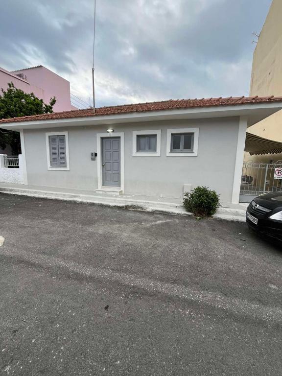 a white house with a car parked in front of it at Cozy House in Argostoli in Argostoli