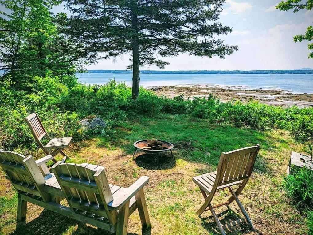 two chairs and a fire pit next to the water at Tideside Beach House in Trenton