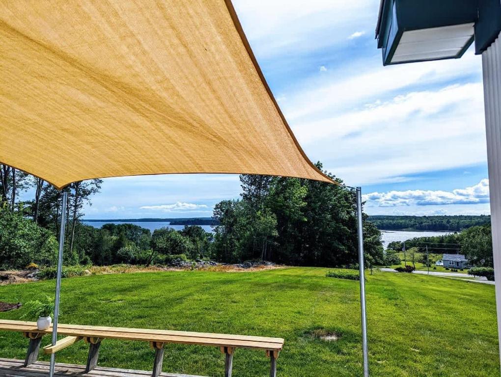 a wooden bench sitting under a large yellow umbrella at Bayside Waterview Cottage in Ellsworth