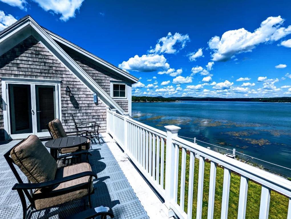 a balcony with chairs and a table and a view of the water at Oceanfront Jellison Beach House in Hancock