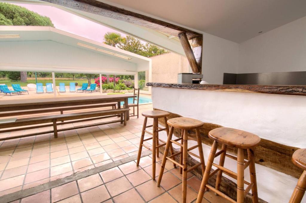un bar avec tabourets et vue sur une piscine dans l'établissement Villa Domaine des Marais, à Saint-Sornin