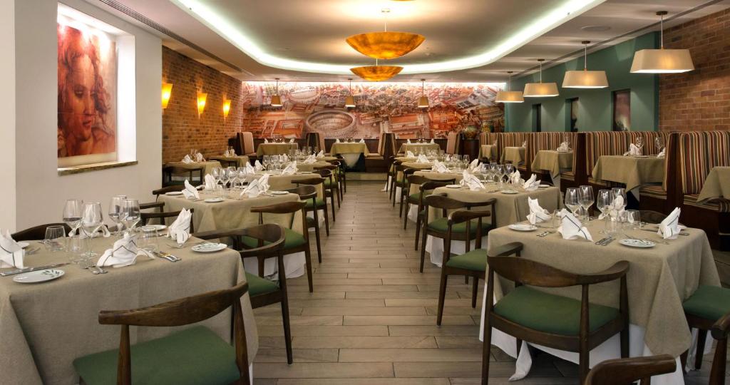 Indoor dining room with beige tablecloths, green chairs, and formal place settings.