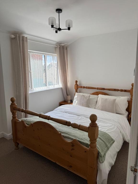 a bedroom with a wooden bed and a window at Valletta House Holiday Apartments in Skegness