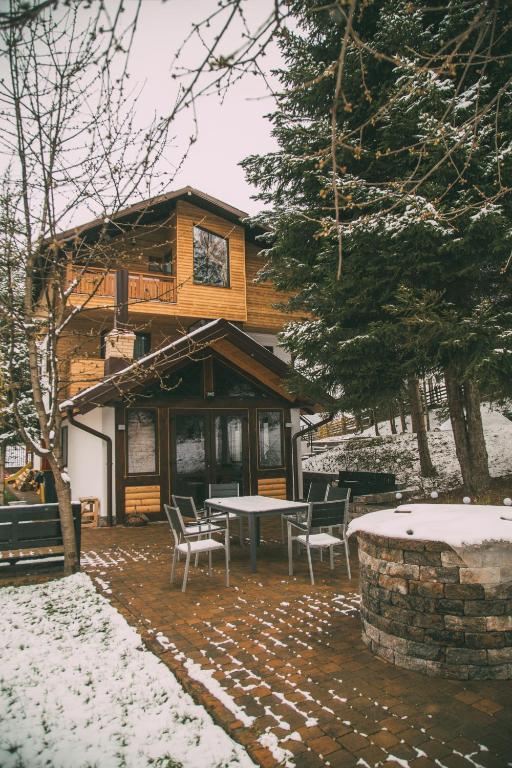 a house with a table and chairs in the snow at Cabana Gura Voronețului in Gura Humorului