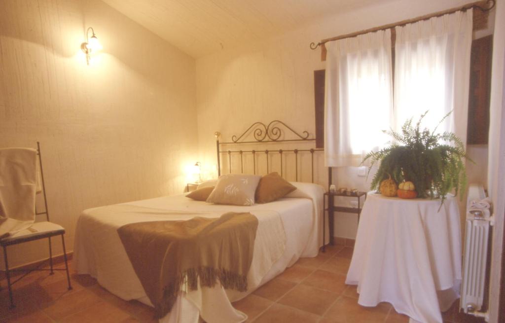 a bedroom with a bed with a table and a window at Casa Rural Nelia in Villalba de la Sierra