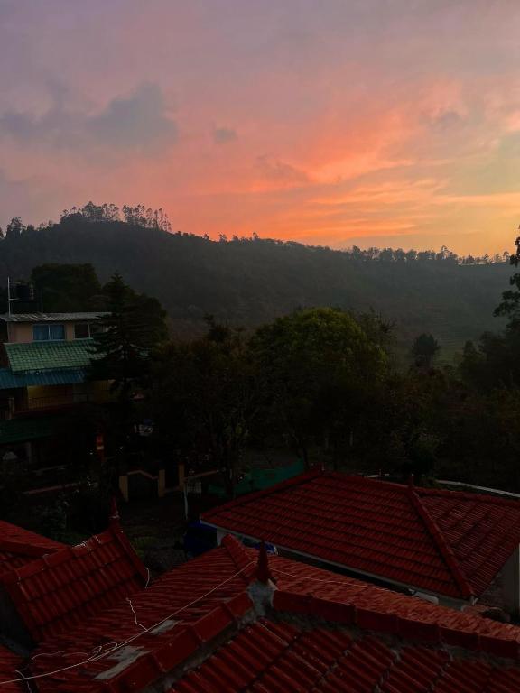 a sunset over the roofs of houses with a mountain in the background at 11 Haven Street Kodaikanal in Kodaikānāl