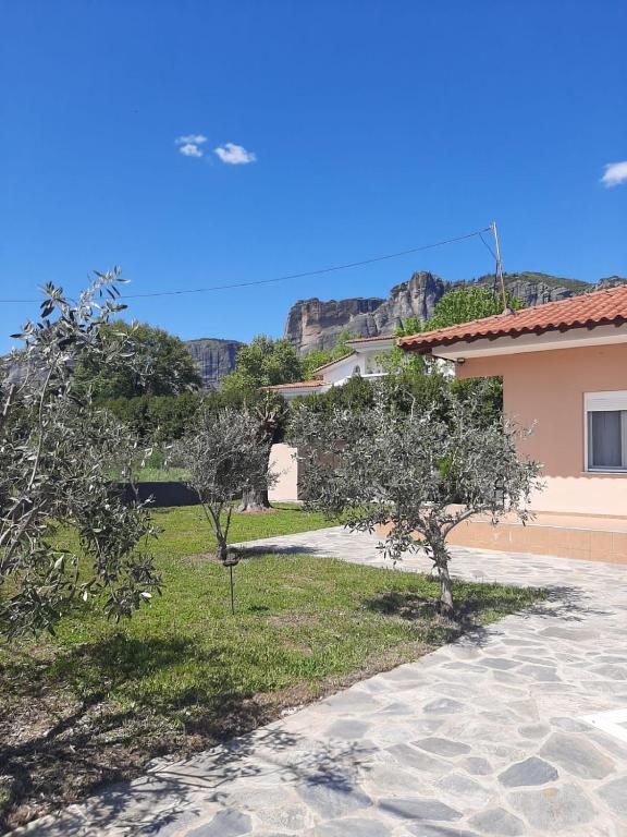 a garden with trees and a building with mountains in the background at Meteora view Guesthouse in Kalabaka