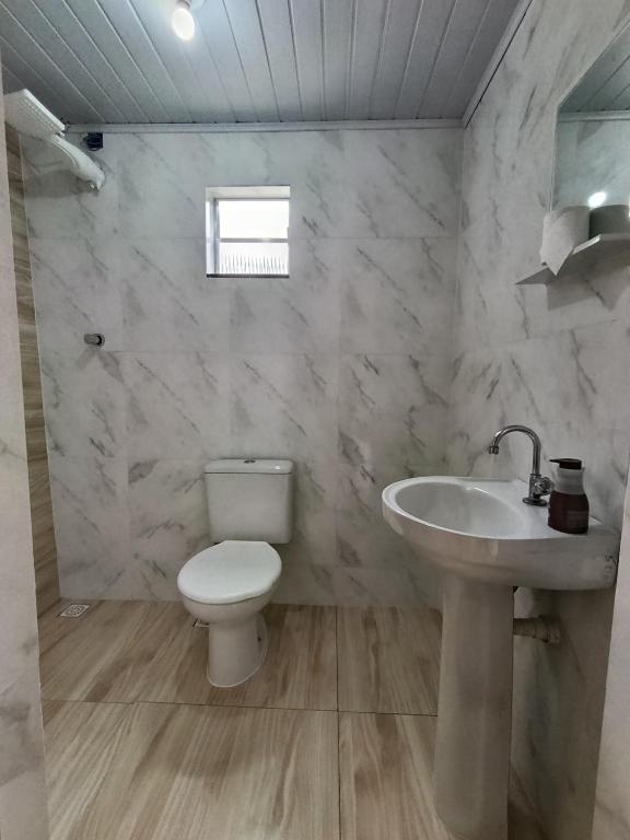 a bathroom with a white toilet and a sink at Chalé do Mato in Itatiaia