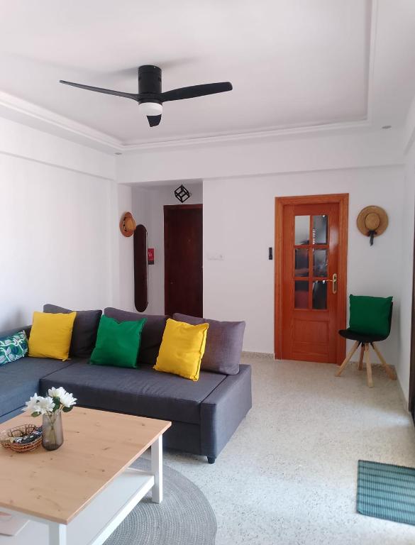 a living room with a blue couch with yellow and green pillows at Beach Apartment in Puerto de Mazarrón