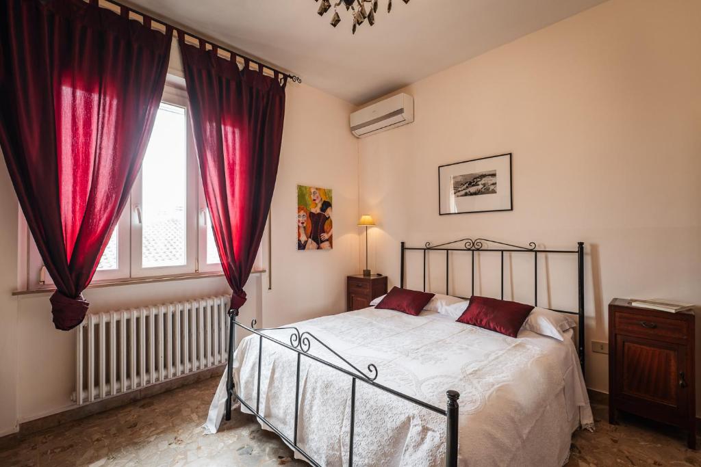 a bedroom with a bed with red curtains and a window at B&B Casa Fuori Casa - 200 mt dal casello autostradale, parcheggio gratuito, garage moto in Senigallia
