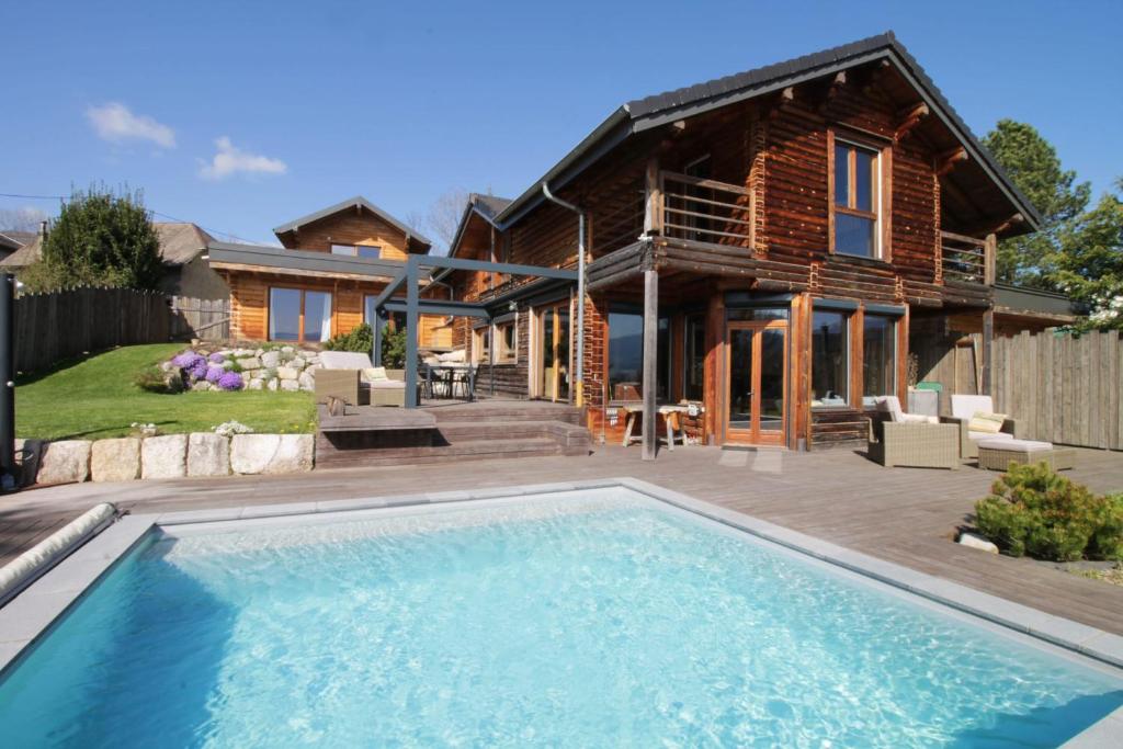 a log home with a swimming pool in front of a house at Formidable Chalet avec piscine et vue in Vimines
