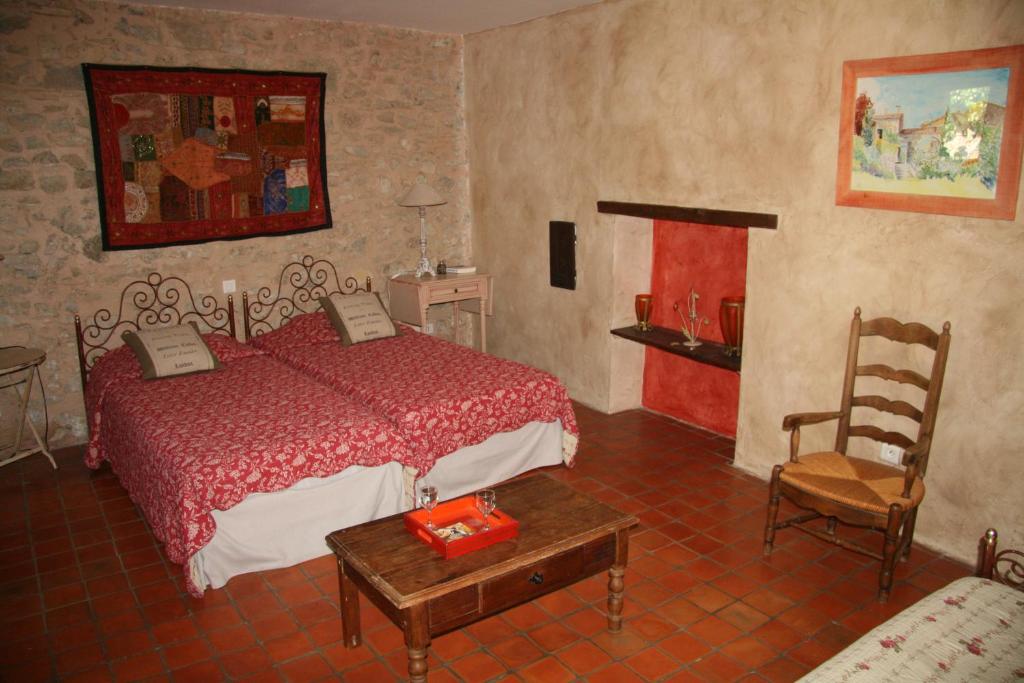 a bedroom with a bed and a table and a chair at Le Jas des Nevières in Pierrerue
