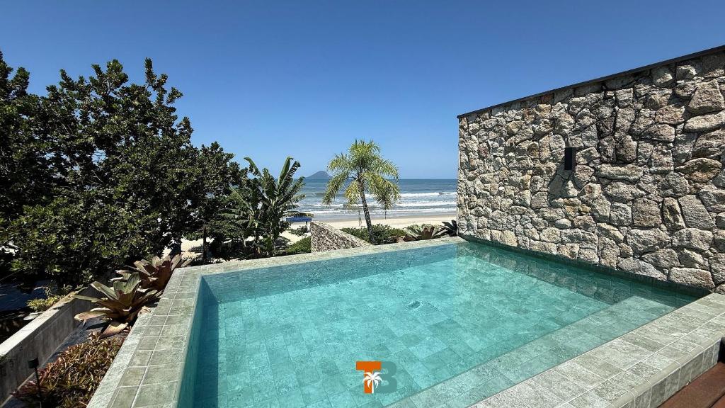 una piscina accanto a un muro di pietra e alla spiaggia di Linda Casa em Juquehy- SP (5) a São Sebastião