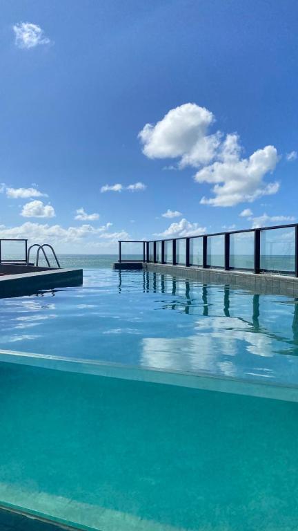 a swimming pool with a view of the ocean at Flat Breeze Maravilhoso in João Pessoa