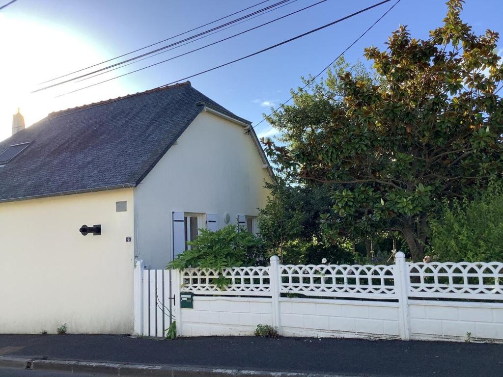 une maison blanche avec une clôture blanche et un arbre dans l'établissement Charmante maison située à 150 m de la plage, à Plérin