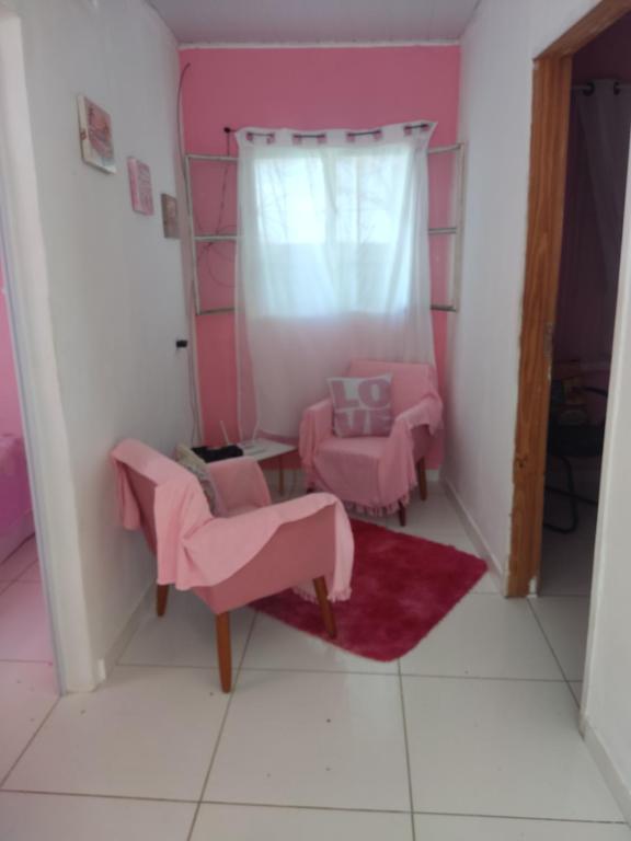 ein Zimmer mit zwei rosa Stühlen und einem Fenster in der Unterkunft aconchegante casa - lagoinha in Nova Iguaçu