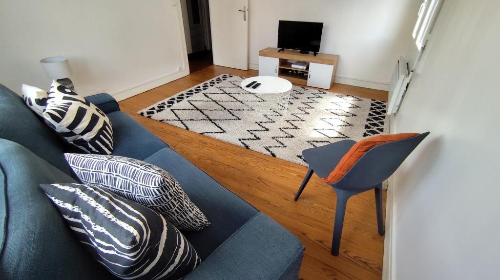 a living room with a blue couch and a chair at Le Haras Ouest in Libourne