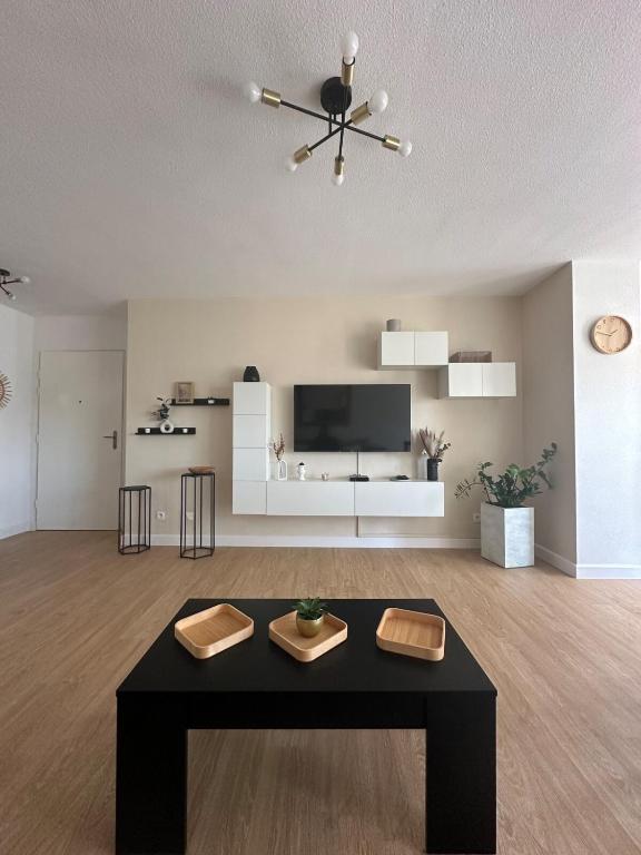 un soggiorno con tavolo nero e TV di Appartement a Port-Saint-Louis-du-Rhône