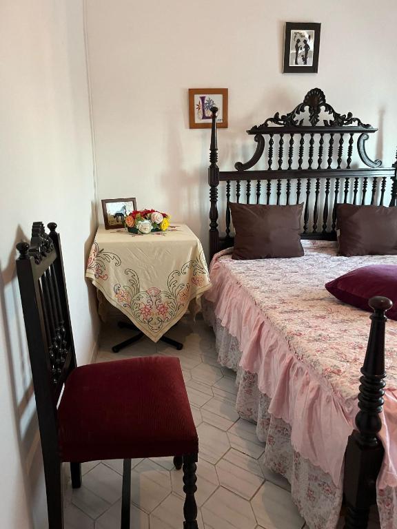 a bedroom with a large bed and a table at Quarto da casa da avó in Cercal